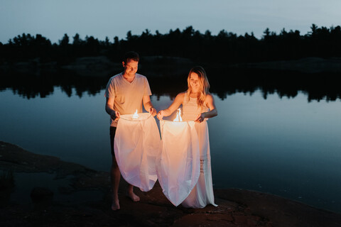 Paar lässt Himmelslaternen am See los, Algonquin Park, Kanada, lizenzfreies Stockfoto