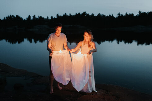 Paar lässt Himmelslaternen am See los, Algonquin Park, Kanada - CUF46366