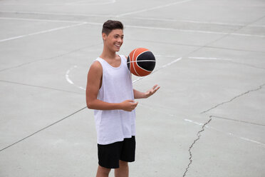 Männlicher jugendlicher Basketballspieler auf dem Basketballplatz, der den Ball wirft und fängt - CUF46449