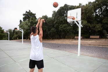 Männlicher jugendlicher Basketballspieler wirft den Ball in Richtung Basketballkorb - CUF46451