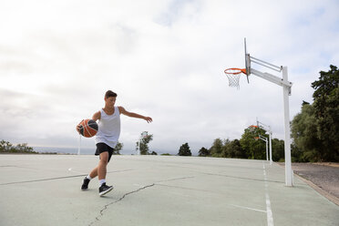 Männlicher jugendlicher Basketballspieler, der mit dem Ball auf dem Basketballplatz läuft - CUF46454