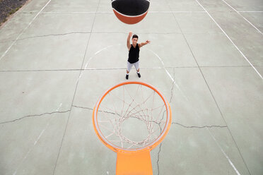 Männlicher jugendlicher Basketballspieler, der den Ball in Richtung Basketballkorb wirft, Blickwinkel - CUF46457