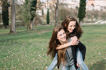 Girlfriends playing piggyback ride in park - CUF46468