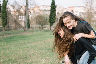 Girlfriends playing piggyback ride in park - CUF46469
