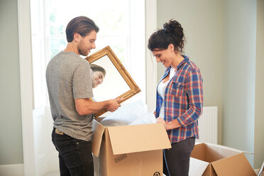Couple packing mirror into cardboard box - CUF46524