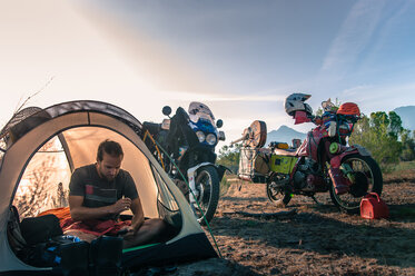 Motorradfahrer benutzt Mobiltelefon im Zelt, Fresno, Kalifornien, USA - ISF20023