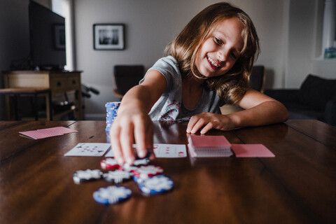 Girl playing cards at table, placing gambling chips stock photo