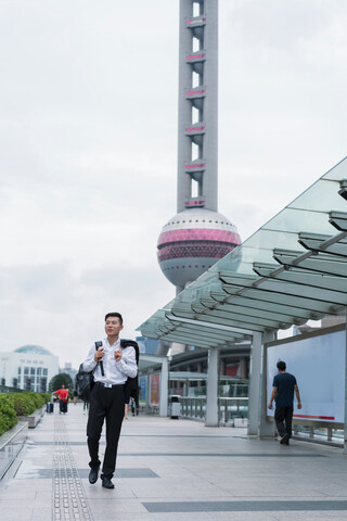 Junger Geschäftsmann beim Bummeln in der Stadt, Shanghai, China, lizenzfreies Stockfoto