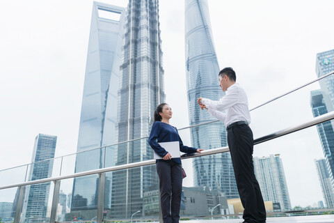 Junge Geschäftsfrau und Mann im Gespräch im Finanzviertel der Stadt, Shanghai, China, lizenzfreies Stockfoto