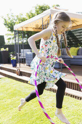 Girl playing with plastic hoop in sunny backyard - CAIF22194