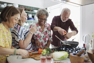 Active senior friends cooking in kitchen - CAIF22214