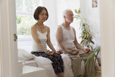 Gelassenes älteres Paar meditiert auf dem Bett - CAIF22228