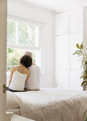 Gelassenes älteres Paar sitzt auf dem Bett und schaut aus dem Fenster - CAIF22229