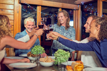 Freunde feiern, trinken Rotwein und genießen das Abendessen in der Hütte - CAIF22239