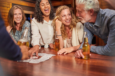 Friends playing card game at cabin table - CAIF22247