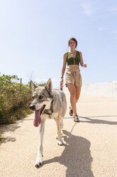 Junge Frau geht mit ihrem Hund auf der Promenade spazieren - WPEF01073