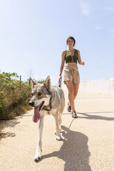 Young woman going walkies with her dog on promenade - WPEF01073