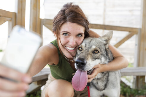 Junge Frau macht Selfie mit ihrem Hund mit Smartphone - WPEF01074