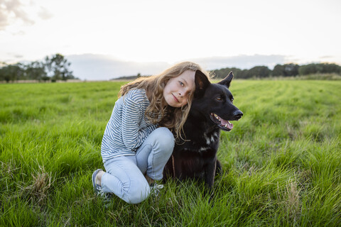 Girl with a dog sitting on a field stock photo