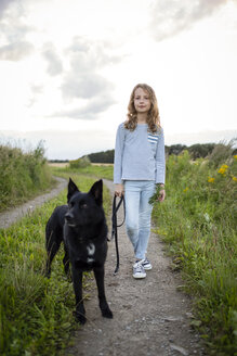 Mädchen mit Hund auf einem Feldweg stehend - OJF00276