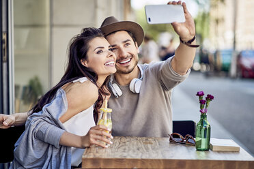 Happy young couple taking a selfie at outdoors cafe - BSZF00789