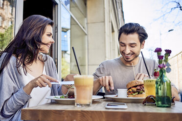 Glückliches junges Paar beim Mittagessen in einem Restaurant im Freien - BSZF00803