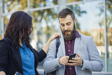 Businessman and businesswoman with cell phone outdoors - ZEDF01699