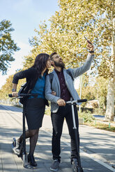 Glückliches Geschäftspaar mit Motorrollern, das ein Selfie macht - ZEDF01718