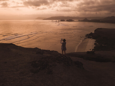 Indonesien, Lombok, junge Frau an der Küste bei Sonnenuntergang, lizenzfreies Stockfoto
