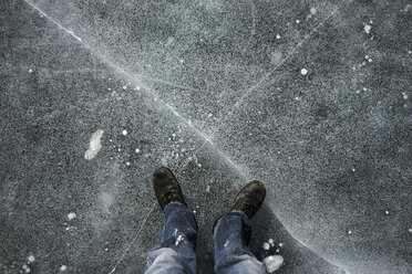 Niedriger Ausschnitt eines Mannes, der im Winter auf der Straße mit einem Kreuzzeichen steht - CAVF51486