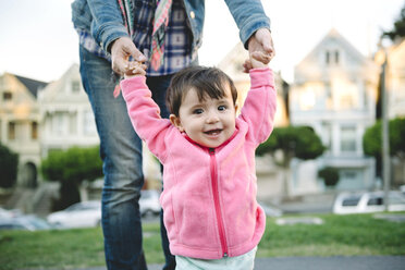 Midsection of mother assisting daughter in walking on street - CAVF51491