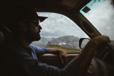 Seitenansicht eines Mannes, der auf einem Berg gegen einen bewölkten Himmel Auto fährt - CAVF51502