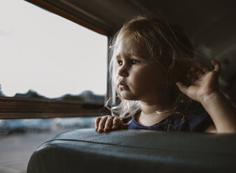 Nahaufnahme eines Mädchens, das durch das Fenster schaut, während es im Bus steht - CAVF51510