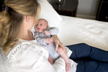 Close-up of mother carrying son while relaxing on bed at home - CAVF51526