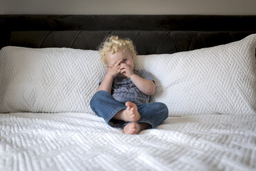 Playful boy lying on bed at home - CAVF51531