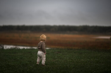 Full length of baby boy looking away while standing on field at park - CAVF51561