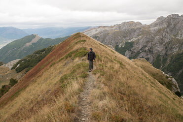 Man walking on mountain against cloudy sky - CAVF51570