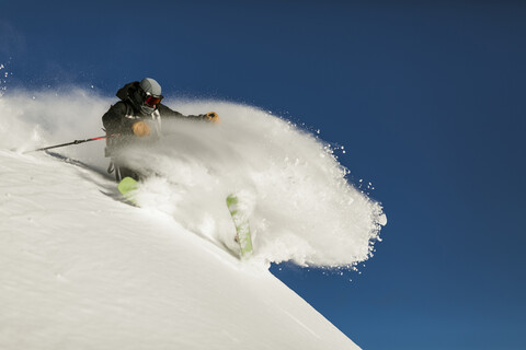 Low angle view of man skiing on snow covered mountain against clear sky stock photo
