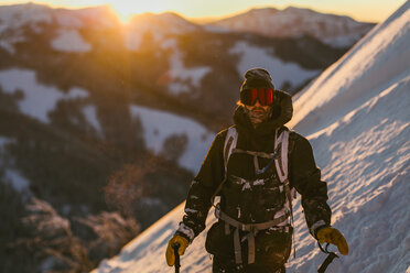Mann in Skikleidung auf einem schneebedeckten Berg bei Sonnenuntergang - CAVF51580