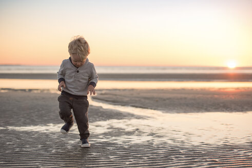 Voller Länge des Jungen zu Fuß am Strand gegen den Himmel bei Sonnenuntergang - CAVF51643