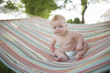 Porträt des niedlichen hemdsärmeligen kleinen Jungen, der auf einer Hängematte im Hinterhof sitzt - CAVF51686