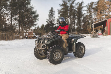 Jugendlicher fährt Quad auf verschneitem Feld - CAVF51690