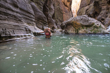 Porträt einer Frau mit Rucksack im Fluss im Zion National Park - CAVF51725