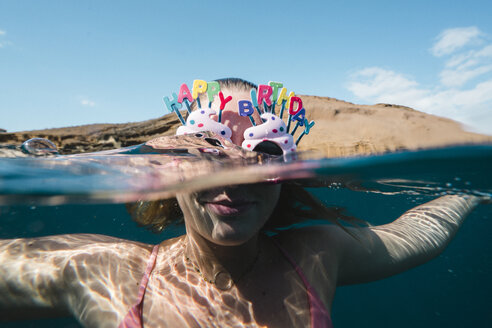 Nahaufnahme einer Frau, die beim Schwimmen im Meer eine Sonnenbrille mit einem Geburtstagsgruß trägt - CAVF51771