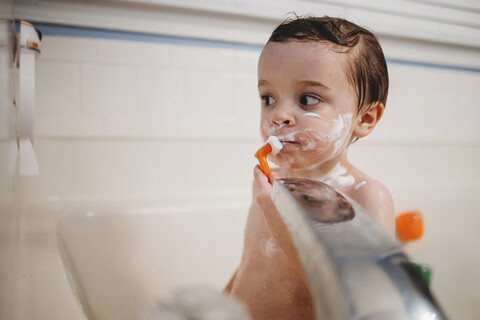 Hemdloser Junge rasiert sich beim Baden in der Badewanne zu Hause, lizenzfreies Stockfoto