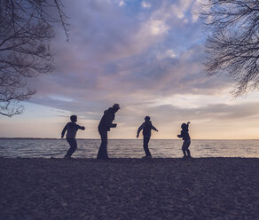 Father and son playing at lakeshore against cloudy sky - CAVF51780