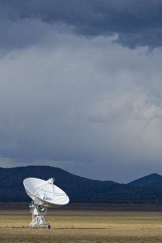 Satellite dish on field against cloudy sky at dusk stock photo