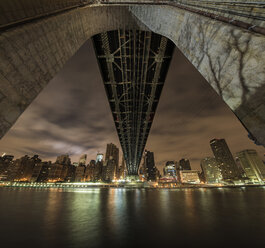 Low angle view of Queensboro Bridge over East River against cloudy sky at night - CAVF51795