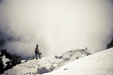 Rückansicht eines auf einem Berg stehenden Mannes bei nebligem Wetter - CAVF51815