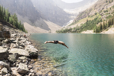 Side view of man diving in lake against mountains at Banff National Park - CAVF51821